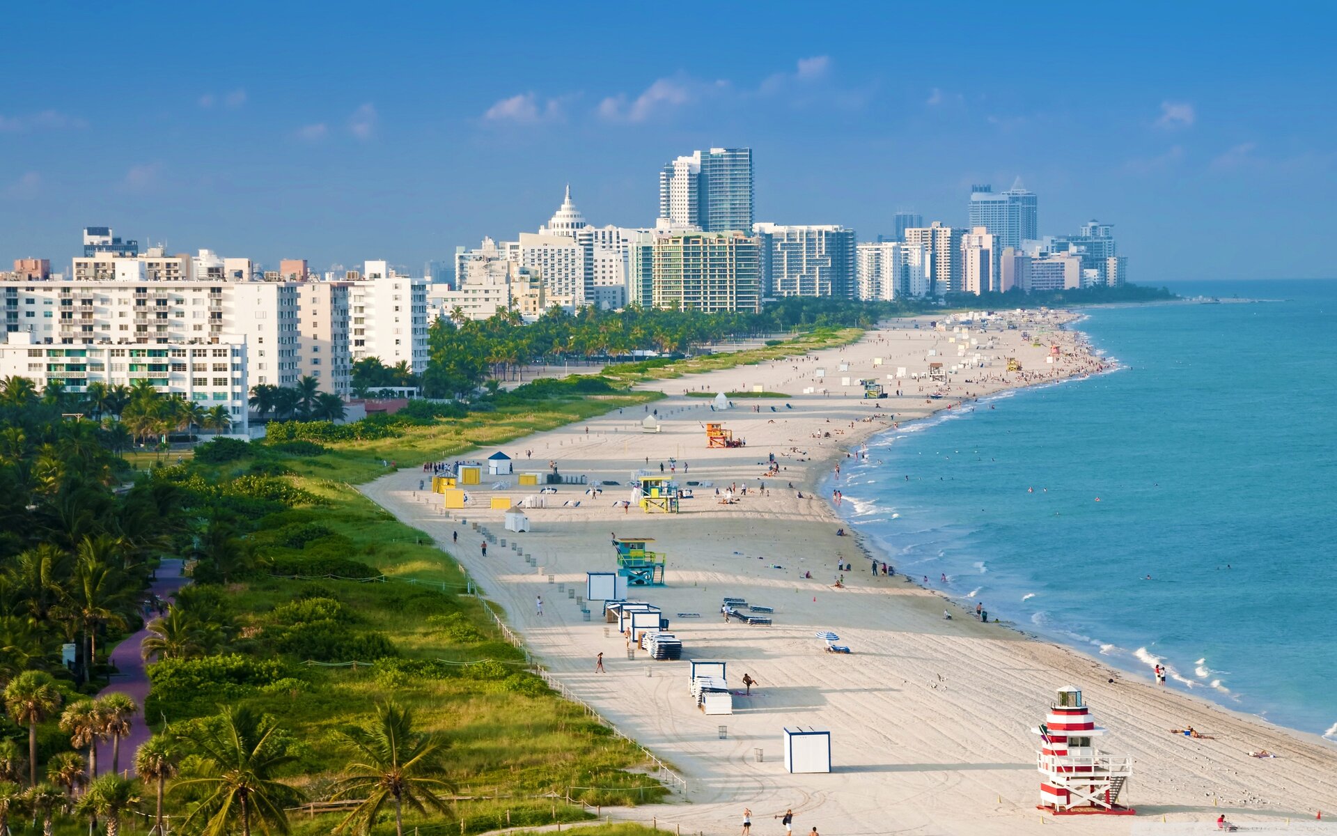 A wide-angle view of a beach with a city skyline in the background.