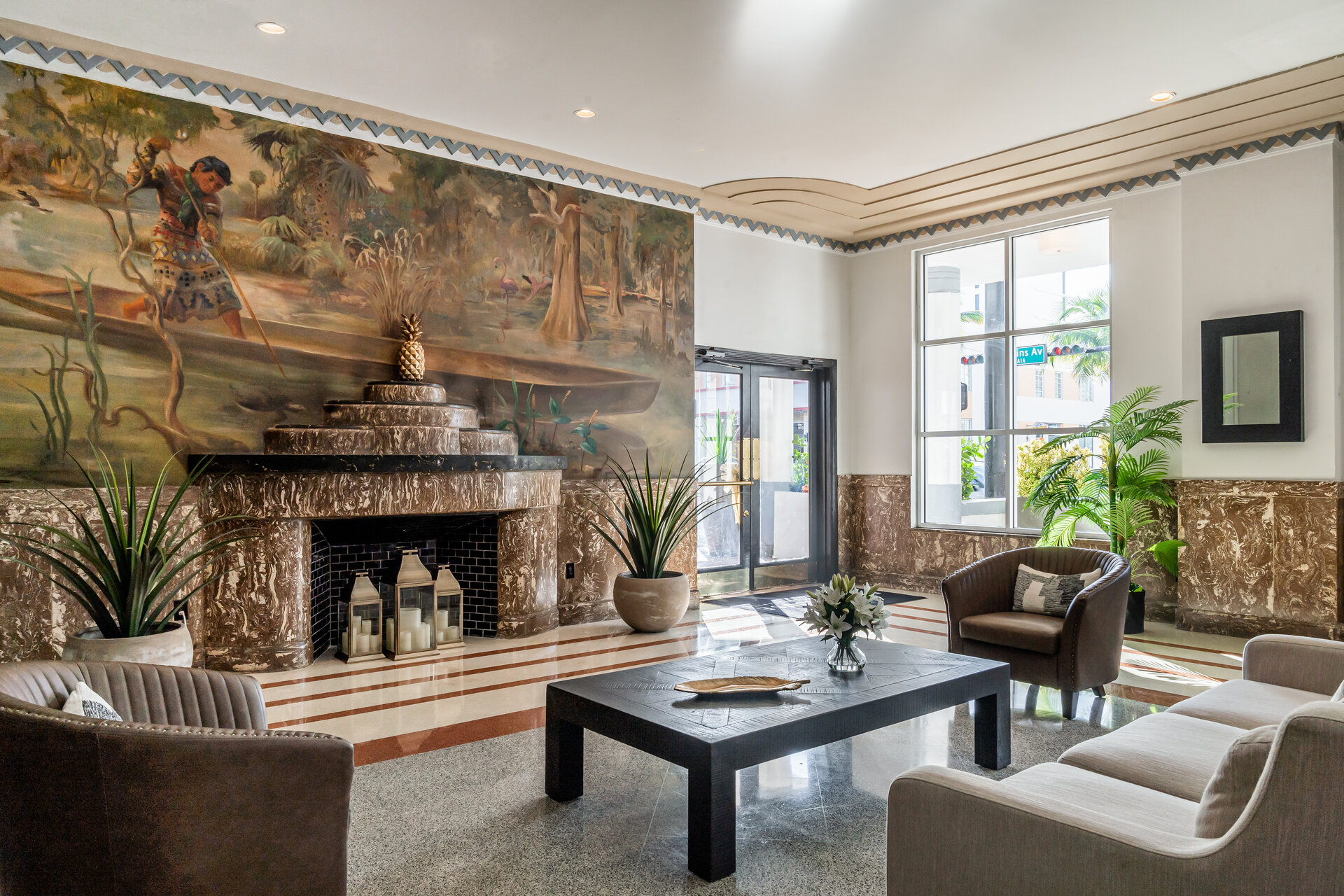 A lobby with a large mural, fireplace, and seating area.